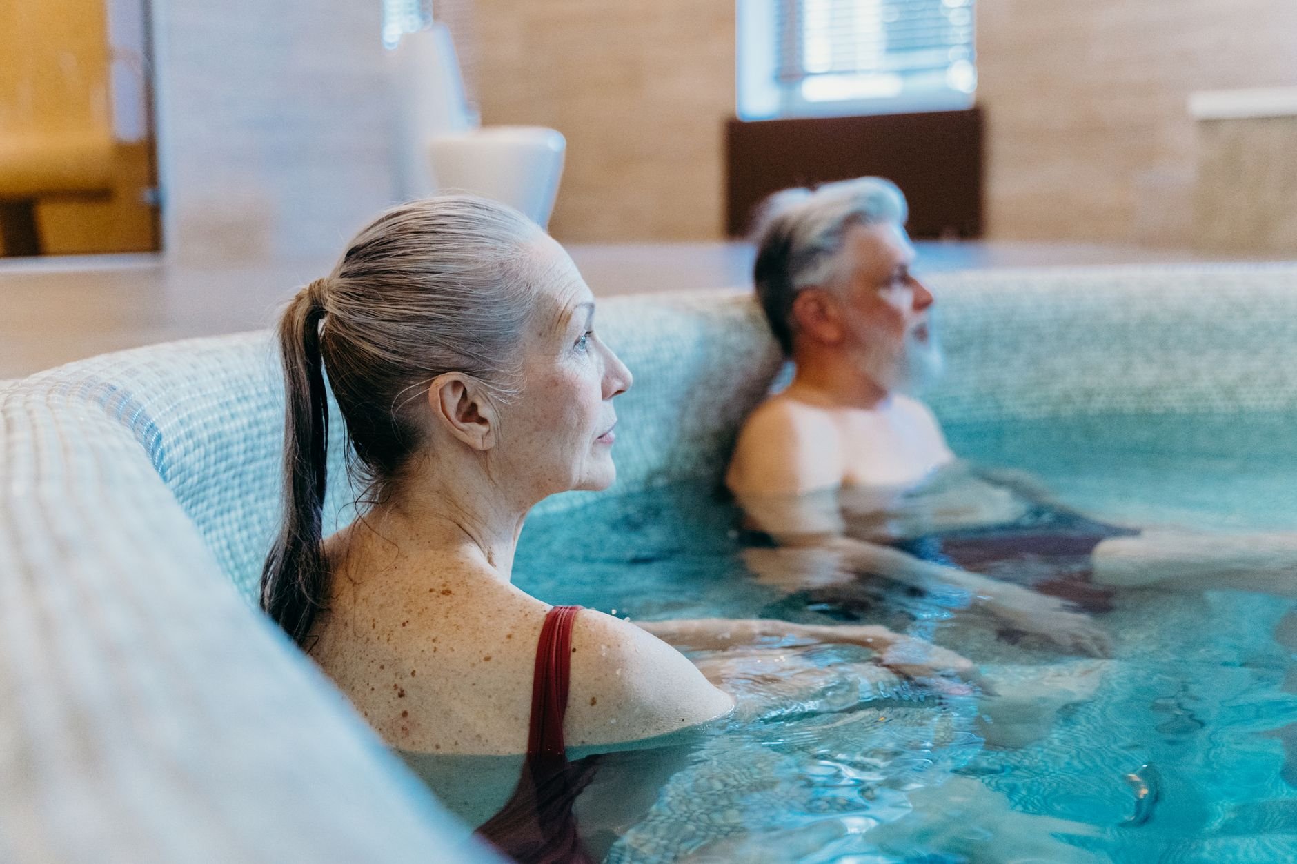 Elderly couple enjoying leisure time in an indoor swimming pool, promoting relaxation and health.